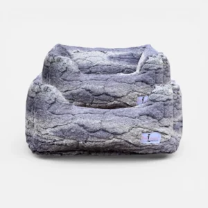 Large grey faux-fur pet bed with two elevated, cushioned levels and a soft, cave-like interior edge for a cozy lounging spot.