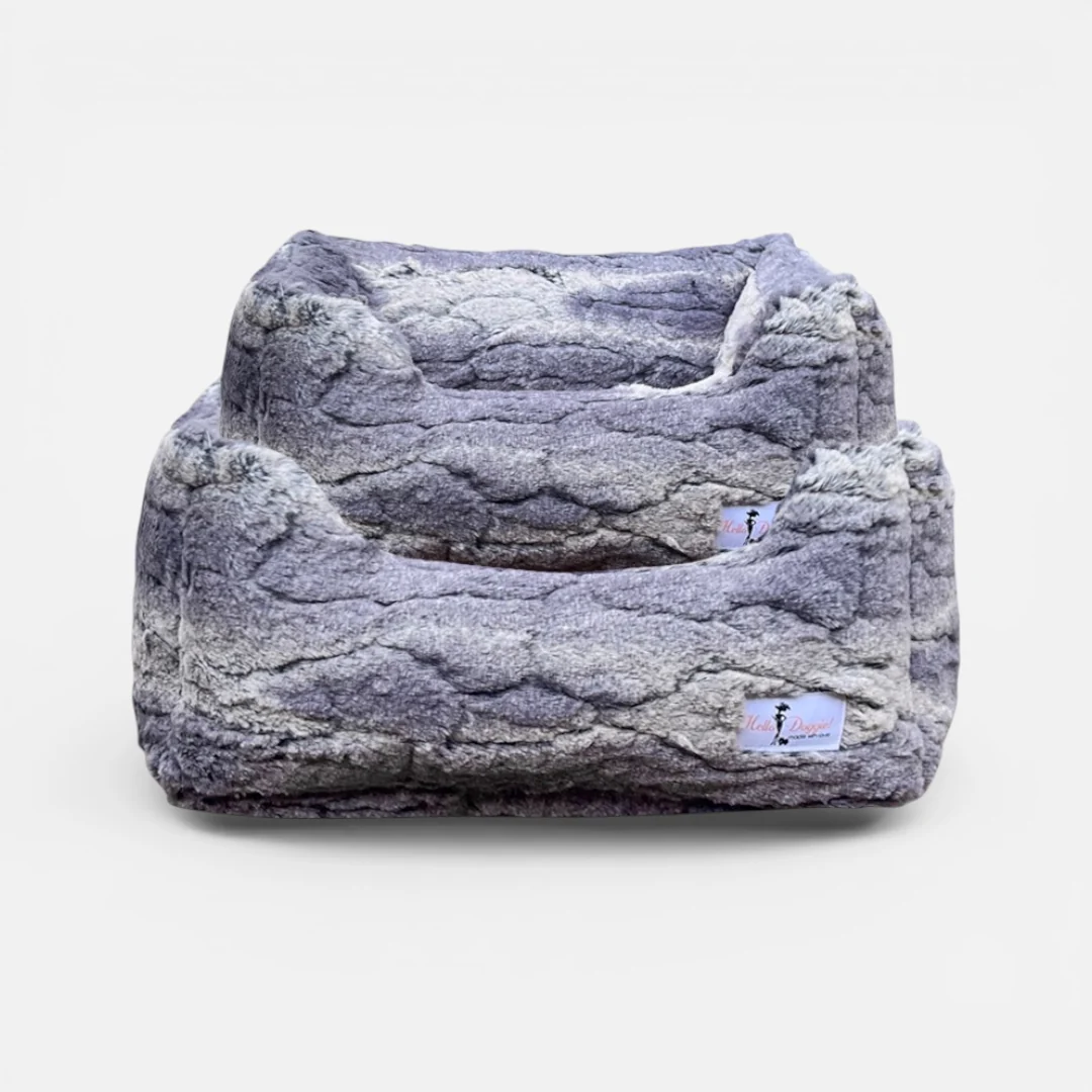 Large grey faux-fur pet bed with two elevated, cushioned levels and a soft, cave-like interior edge for a cozy lounging spot.
