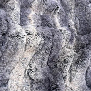 Close-up of a grey, fibrous rock surface with wave-like ridges and a soft, fur-like texture.